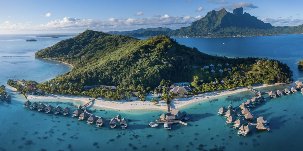 an island in the south pacific with a lush jungle and mountains and a hotel resort with overwater villas